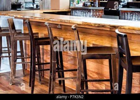Row of empty wooden vintage bar stools by counter in drink establishment pub during day pattern closeup, retro wood and nobody Stock Photo