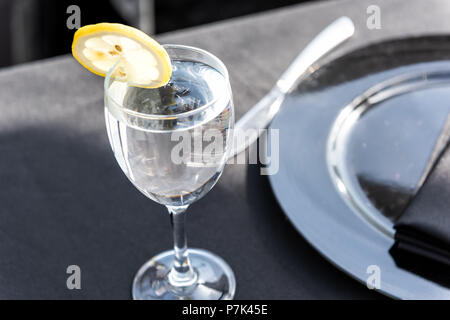 Closeup of one glass with lemon slice and water in restaurant or wedding reception black table tablecloth background Stock Photo