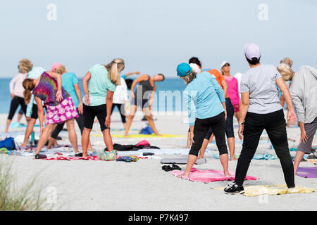 Venice, USA - April 29, 2018: Small Florida retirement city, town, or village community with people practicing exercising yoga on the beach, stretchin Stock Photo