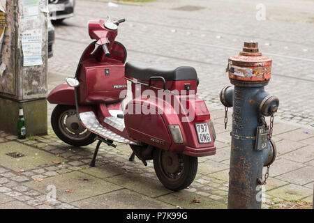 Old Vespa next to a fire hydrant on the roadside Stock Photo