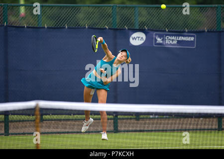 Katie Swan, professional British tennis player, in the middle of a serve during a match at the 2018 Nature Valley Open. Swan is pictured in the air with the ball, visible in shot, having left her racket.