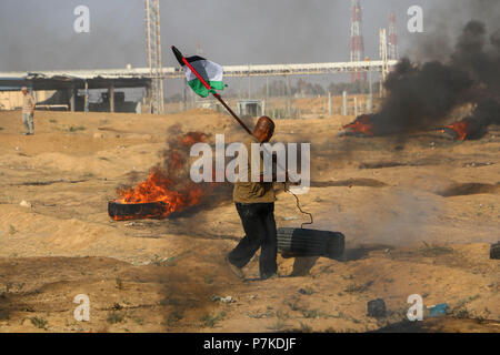 Gaza, Palestine. 6th July 2018. A Palestinian man seen raising the flag of Palestine. Protest against the recognition of Jerusalem as the capital of Israel that resulted into injuries among Palestinian citizens who were fired with live bullets and tear gas canisters by the Zionist occupation forces on the border of the Gaza Strip near the site of Nahal Oz east of Gaza City. Credit: SOPA Images Limited/Alamy Live News Stock Photo