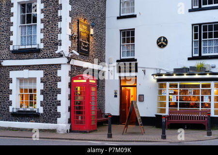 red telephone booth in front of The Dolphin Hotel, Beer, Devon, England, UK Stock Photo