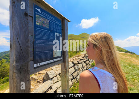 A girl reads an informative sign at the Alpe Colonno, Pigra, Val d'Intelvi, Como Lake, Lombardy, Italy, Europe. Stock Photo