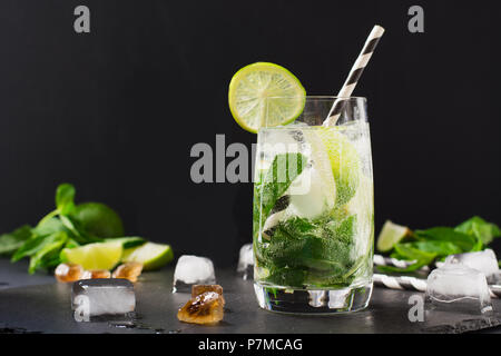 Mojito cocktail in glass with garnish on black table. Low key photo. Close up. Stock Photo