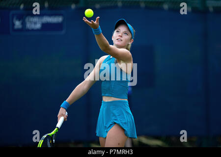 Katie Swan, professional female tennis player, releases the tennis ball into the air ready to serve during a match.