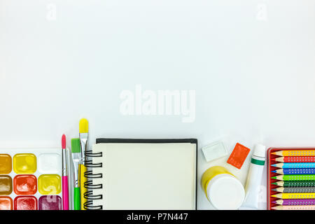 back to school concept. notebook, pencils, paints on white desk surface, flat view Stock Photo