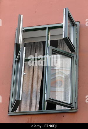 Close-up of four open windows on a red wall.. Stock Photo