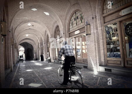 Senior man rides old bicycle along arched alleys of traditional Silk Road era Middle East bazaar market of Qazvin, Iran Stock Photo