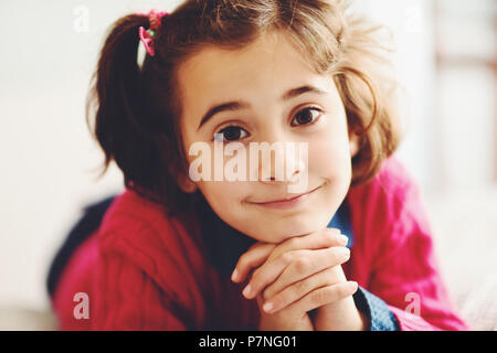 Adorable little girl with sweet smile lying down on bed. Close-up potrait. Stock Photo