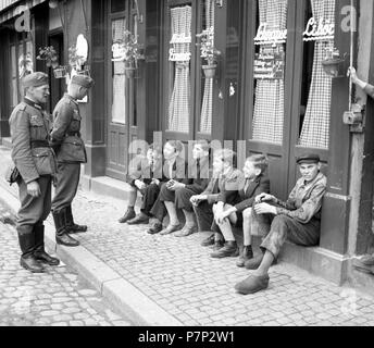 Approx. 1939,1941, training Wehrmacht, two soldiers talking to boys sitting on the curb, Ulm, Germany Stock Photo