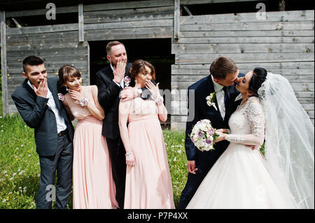 Bridesmaids with groomsmen and wedding couple having fun outdoors next to the old rustic wooden barn. Stock Photo