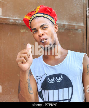 Young Cuban man smiling and smoking a cigar in Havana, Cuba Stock Photo
