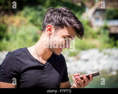 Young man in park using cell phone Stock Photo