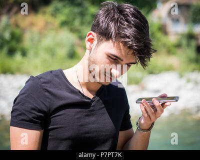 Young man in park using cell phone Stock Photo
