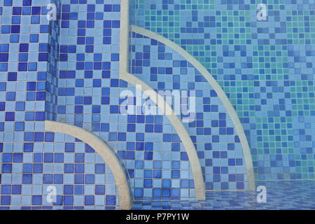 A captivating top view of a swimming pool adorned with pixelated blue tiles, creating a gradient effect. The focal point is on three quarter-circle-sh Stock Photo