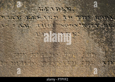 Worn our stone surface with partly readable engraved Latin letters Stock Photo