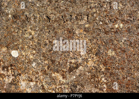 Worn rusty metal surface with partly readable engraved Latin letters Stock Photo