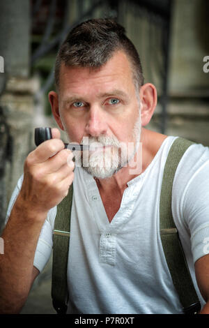 portrait of handsome bearded man in his 50s smoking a pipe Stock Photo