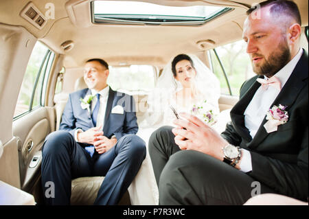 Fabulous wedding couple and groomsman sitting in the car before the ceremony. Stock Photo