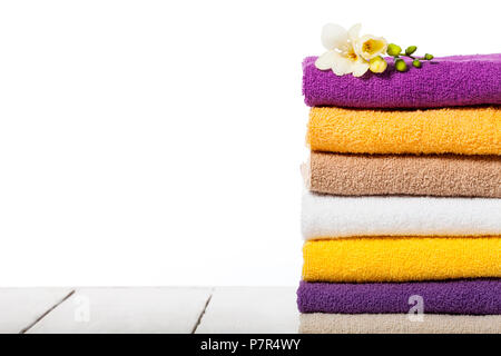 Stack of bath towels on light wooden table and white background closeup Stock Photo