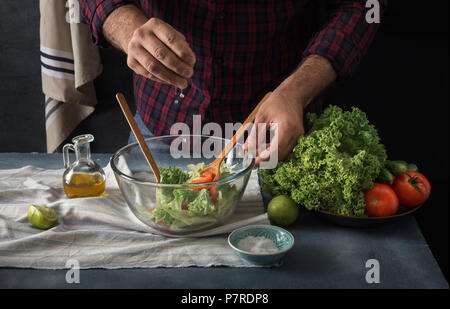 Man cooking vegetables salad in home kitchen. Male hands pouring lemon juice into salad Stock Photo