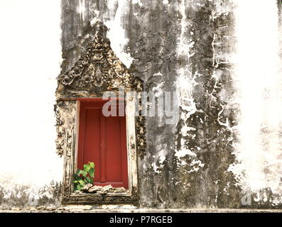 the red ancient wooden door and art strip of arched entrance on ancient building facade Stock Photo