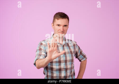 Portrait of european serious young man stretching hand towards camera with stop or hold gesture Stock Photo