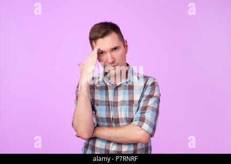 young man thinking against pink background. He is not sure in future plans. Need Stock Photo