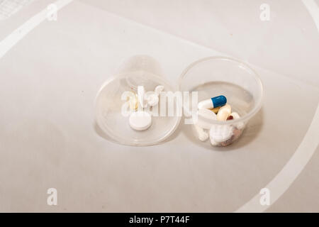 Two plastic containers, one on its side, with different medicines in them Stock Photo