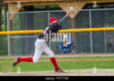 Pitcher delivering pitch, in full stride, boys afternoon junior baseball game. Cranbrook, BC. Stock Photo