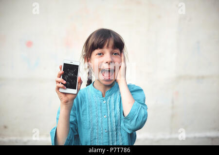 Broken glass screen smartphone in hand of upset girl, white background. Stock Photo