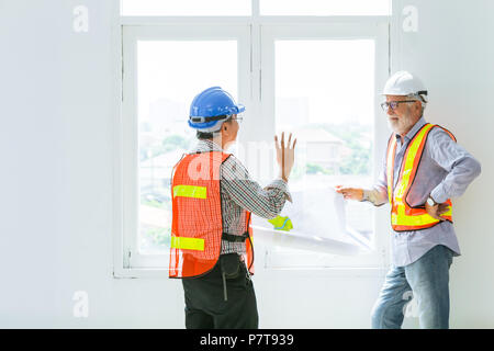 mix race senior construction engineers worker talking together about future of design with blueprint Stock Photo