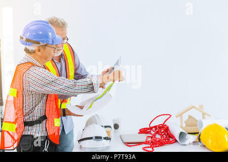 mix race senior construction engineers working together looking blueprint and discussion. Stock Photo