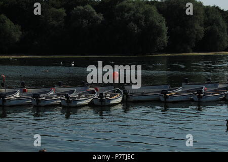 Landscapes - Line of fishing boats moored on the water on a late afternoon at Hanningfield Reservoir, Essex, Britain. Stock Photo