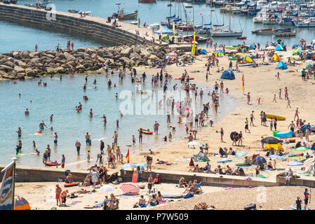 Lyme Regis, Dorset, UK. 8th July 2018.  UK Weather: Another scorching hot and sunny Sunday in Lyme Regis. The Jurassic Coast roasts again as visitors and locals flock to the beach on yet another sizzling Sunday on the south coast. Beachgoers take a cooling dip in clear blue sea on the hottest day of the year. Credit:  Celia McMahon/Alamy Live News Stock Photo