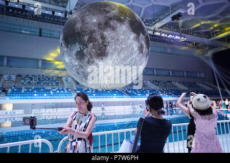 Beijing, China. 8th July, 2018. Visitors take photos of a huge moon model during an exhibition on moon held at the National Aquatic Center or 'Water Cube' in Beijing, capital of China, July 8, 2018. An exhibition on China's Lunar Exploration Technology and 'Museum of the Moon' opened Sunday in Beijing. Credit: Ju Huanzong/Xinhua/Alamy Live News Stock Photo