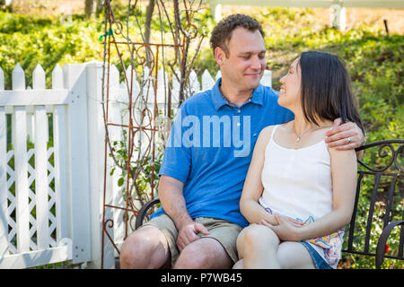 Young Caucasian Man and Chinese Woman Sitting On Bench Stock Photo