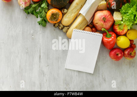 Top view set of raw food with a notebook on white wooden background. Healthy food concept Stock Photo