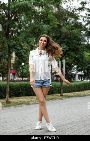 smiling young woman with headphones dancing in park Stock Photo