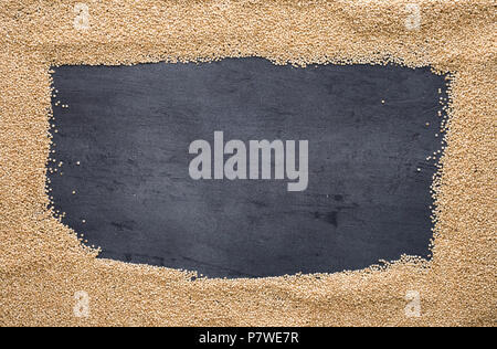 Frame of raw quinoa on dark background, top view Stock Photo