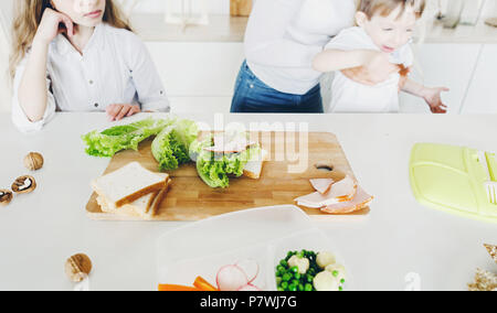 Mother preparing school snack or lunch for childrens in home kitchen in the morning Stock Photo