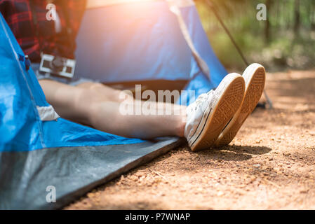 Close up of woman strecthing feet with shoe with nature background. Tourist woman resting in camping tent. People and lifestyles concept. Holiday and  Stock Photo