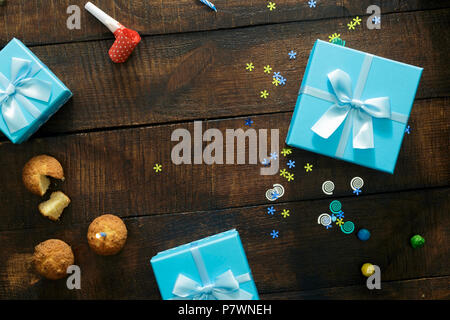 Frame from cupcakes with a candle and gift boxes on wooden background, top view. Holiday background Stock Photo