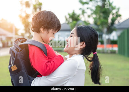 Mom hug and carry her son. Preparing to send her children back to school in morning. Mother playing with kids. Education and Back to school concept. H Stock Photo