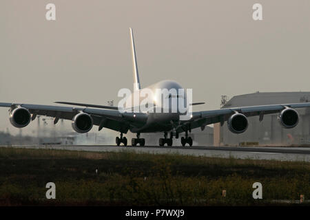 Airbus A380 four-engine long haul passenger jet airplane landing on runway with tyre smoke on touchdown. No livery or proprietary details visible Stock Photo