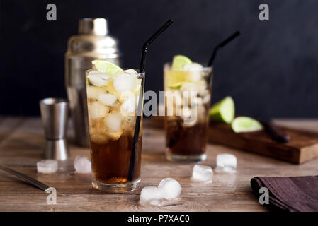 Rum and Cola Cuba Libre drink with lime and ice on rustic wooden table Stock Photo