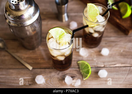 Rum and Cola Cuba Libre drink with lime and ice on rustic wooden table Stock Photo