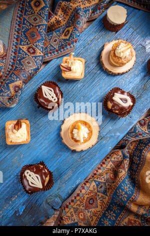 Different small cakes standing on a blue wooden board Stock Photo