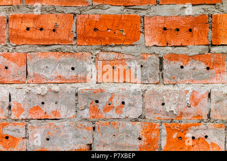 Wall of red brick with holes and gray cement. Stock Photo